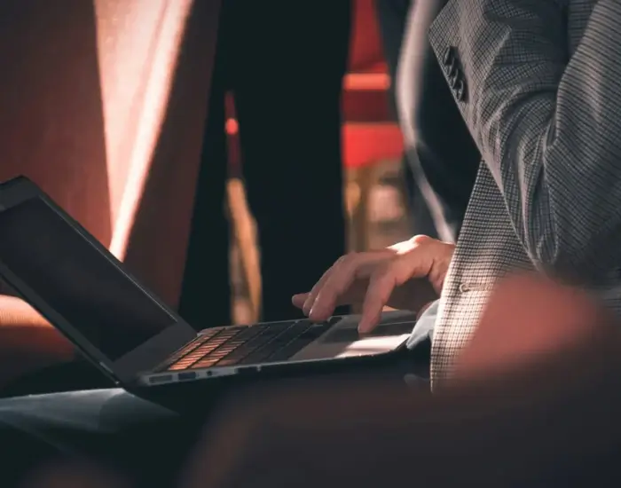 A close-up of a person's hands typing on a laptop keyboard.